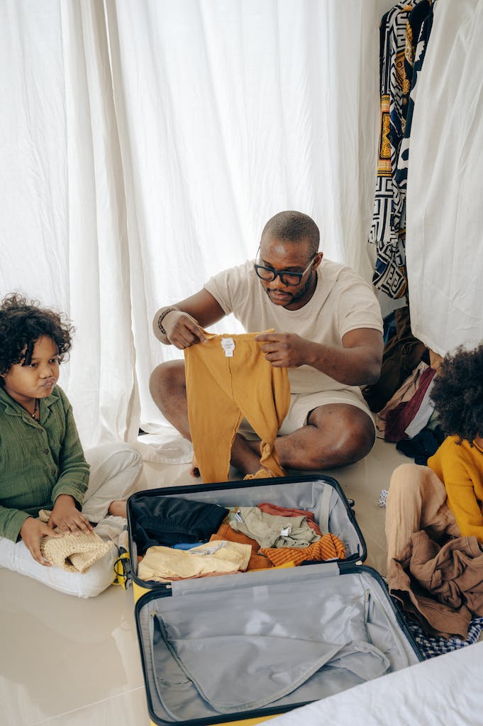 Black man with kids sitting on floor near suitcase