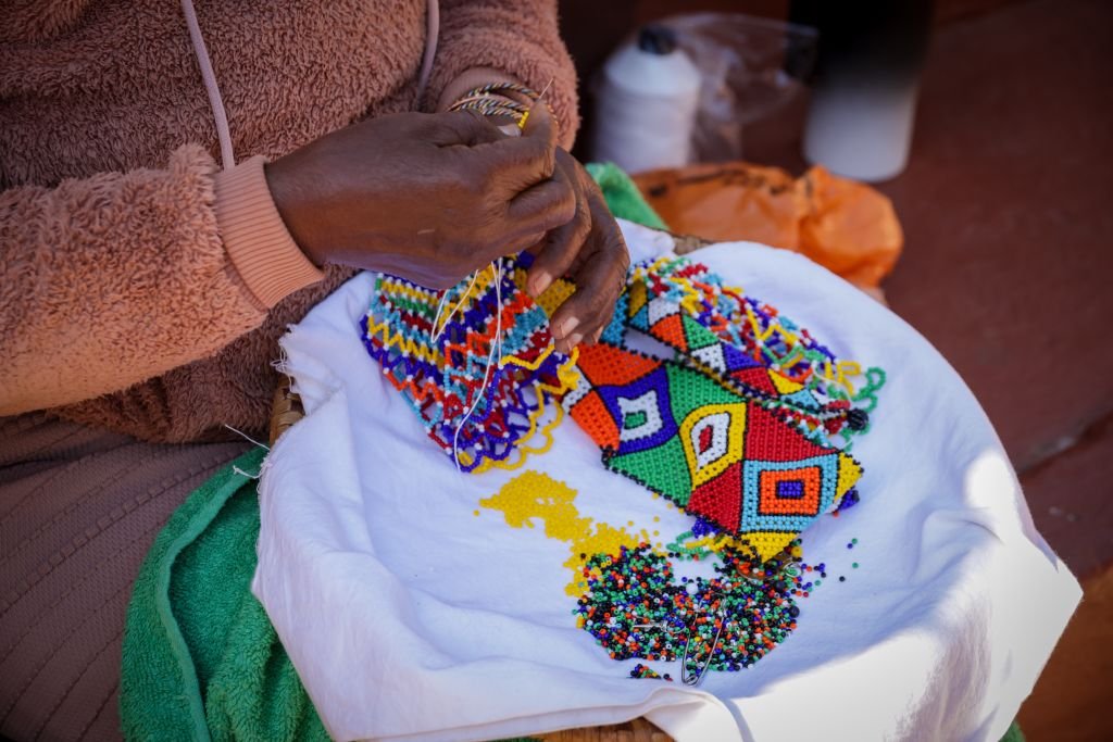 Close-up of a person creating vibrant beaded art with intricate patterns.