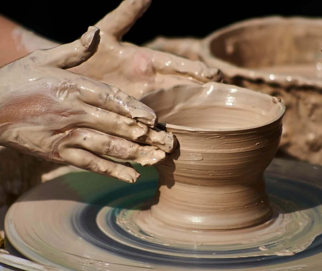 Close-up of hands shaping pottery on a wheel, showcasing artisan skills.
